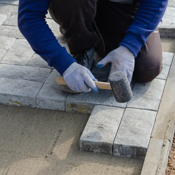 Professional installers preparing and laying block paving driveway.